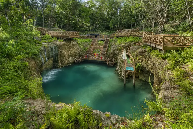 Cenote Blue Hole con puente de madera sobre el agua turquesa, en plena selva