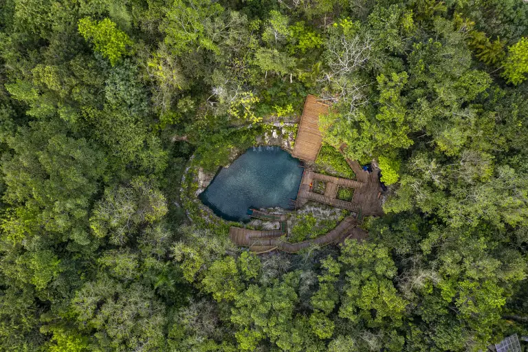 Vista aérea del cenote Blue Hole y su piscina turquesa en el corazón de la selva