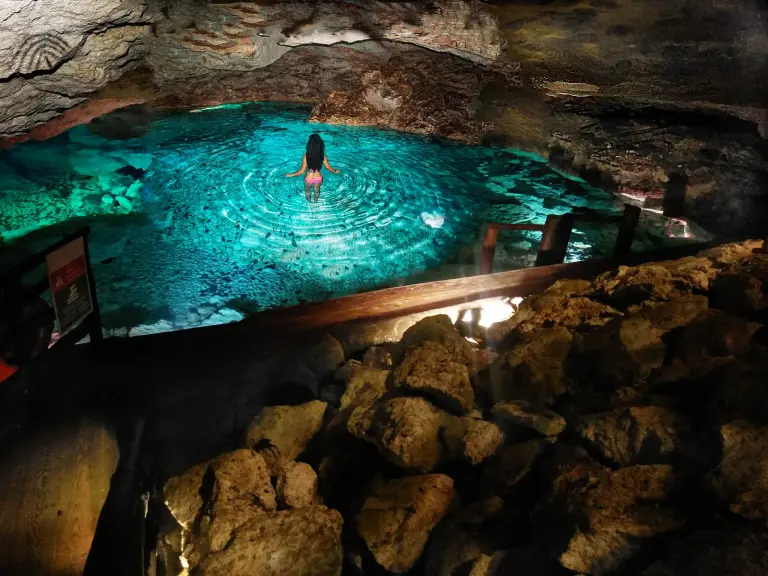 Baño en la piscina turquesa de una cueva subterránea iluminada, en Scape Park