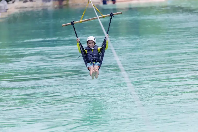 Persona colgada de una tirolina sobre el agua turquesa de un cenote