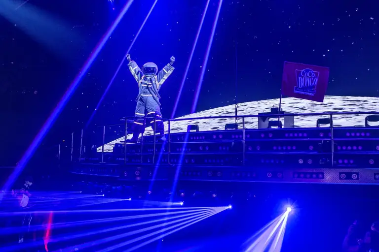Artista sobre un escenario iluminado con luces azules durante el show nocturno