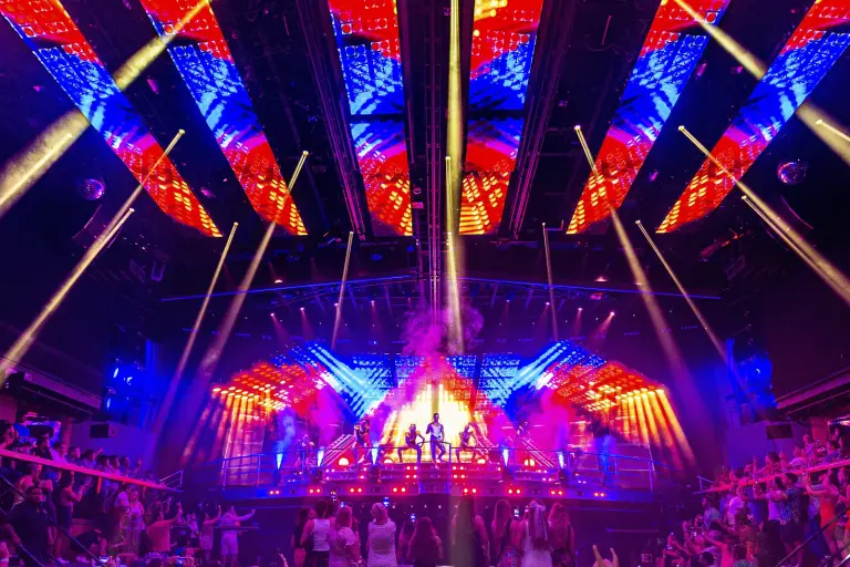 Escenario iluminado con luces rojas y azules y el público de pie