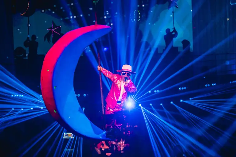 Artista sobre una luna decorativa iluminada de azul durante el show