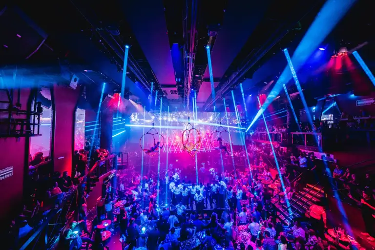 Vista amplia de la discoteca-espectáculo llena de público bajo las luces