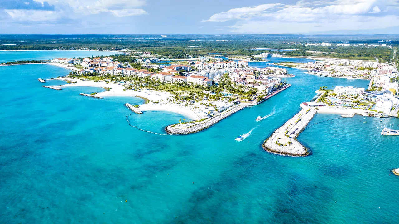Vista aérea de una marina de la República Dominicana: villas de tejados rojos, playa de arena blanca y agua turquesa